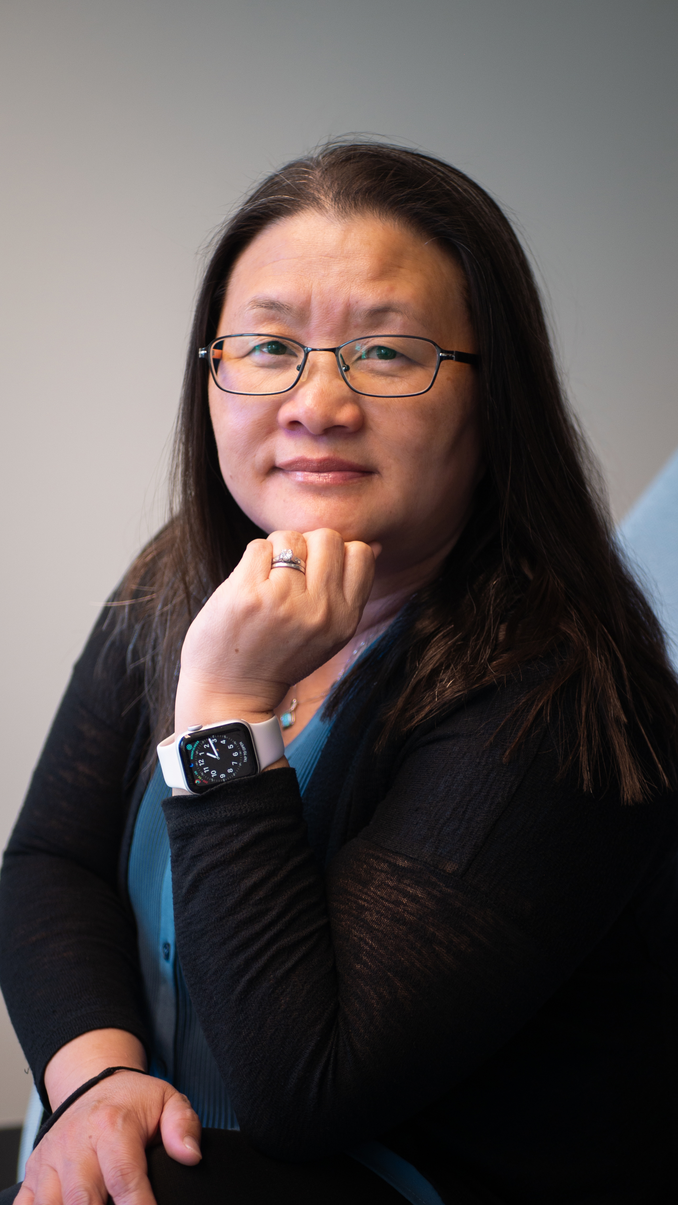 Nhia Cheng, Counselor, sits in a chair smiling.